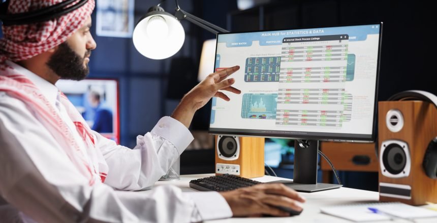 An Arab businessman diligently analyzing data on his computer, making important decisions for the company. Muslim guy wearing traditional attire is checking charts and data on his desktop pc.